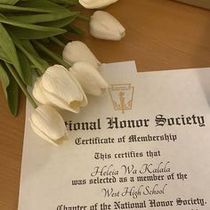 a certificate is laying on top of a table next to tulips and flowers