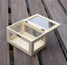 a small wooden box sitting on top of a wooden table next to a glass window