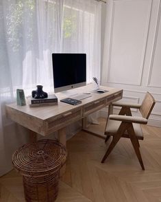 a wooden desk with a computer on top of it next to a wicker stool