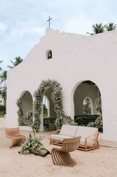 an outdoor seating area in front of a white building with arches and ivy growing on it