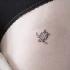 a small turtle tattoo on the side of a woman's stomach is shown in black and white