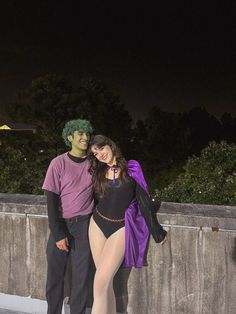 a man and woman dressed in costumes standing next to each other on a bridge at night