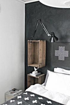 a black and white bedroom with a wooden crate on the wall next to the bed