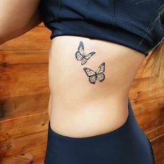 a woman's stomach with three butterflies on her side and the lower part of her abdomen