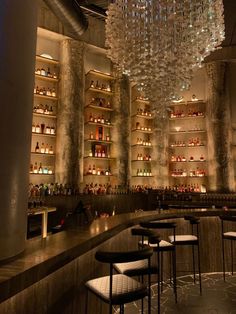 a dimly lit bar with lots of liquor bottles on the shelves and chandelier