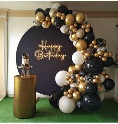 a happy birthday balloon arch with black, gold and white balloons in front of it