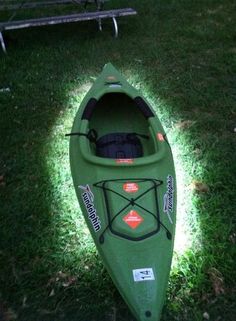 a green kayak sitting on top of a lush green field