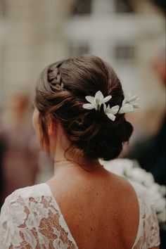 the back of a woman's head with flowers in her hair, wearing a white dress