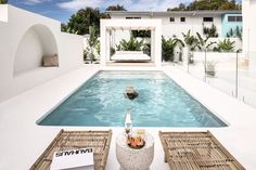 an outdoor pool with wicker chairs and a bottle on the table next to it