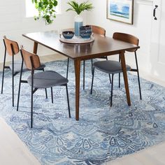 a dining room table with four chairs and a rug