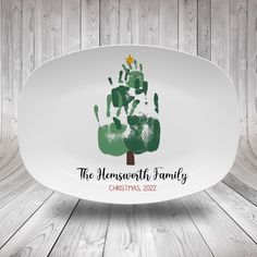 a white platter with a green handprinted christmas tree on it and the words, the anniversary family