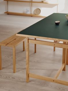 a green table with two benches on it in front of a shelf and bowl of fruit