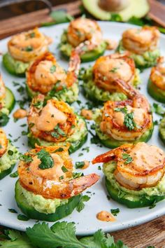 shrimp and avocado stuffed cucumbers on a white plate with garnish