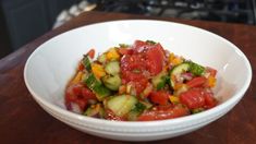 a white bowl filled with cucumber and tomato salad