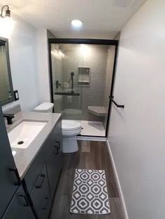 a bathroom with a white toilet sitting next to a walk in shower and wooden floors