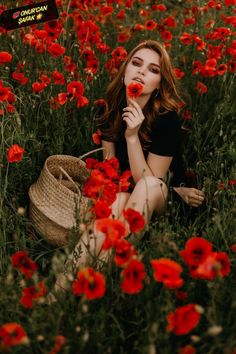 a woman sitting in the middle of a field of red flowers with her hand on her face