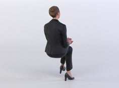 a woman in a black suit and high heels is sitting on a chair with her legs crossed