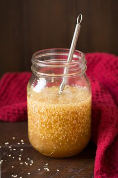 a jar filled with sesame seeds on top of a wooden table next to a red towel