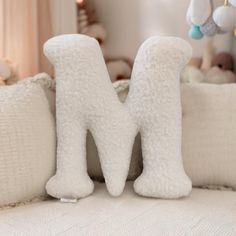 a white stuffed animal sitting on top of a bed next to pillows and toys hanging from the ceiling