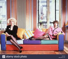 two women sitting on a colorful couch with pillows