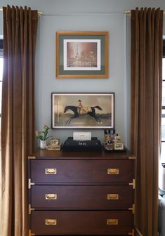 a dresser with drawers and pictures on the wall