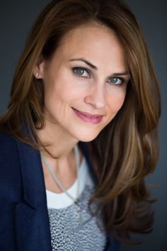 a woman with long hair and blue eyes smiles at the camera while wearing a blazer