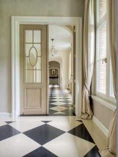 a hallway with black and white checkered flooring next to a doorway that leads into another room