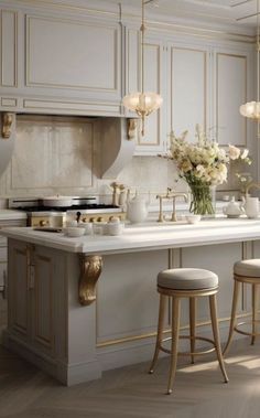 an elegant kitchen with white cabinets and gold trim on the countertop, along with stools