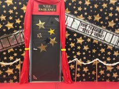 a door decorated with gold stars and red drapes for the entrance to an event