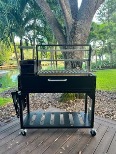 an outdoor grill on a deck next to a tree