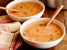 two bowls filled with soup on top of a wooden table