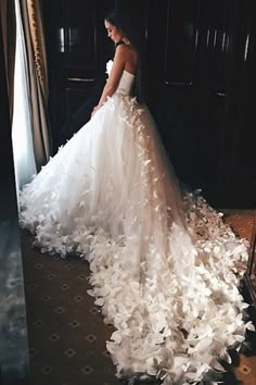 a woman in a wedding dress standing next to an open door with petals on it