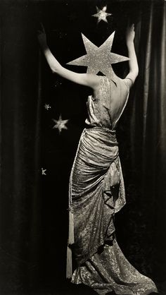 an old photo of a woman in a dress with stars on her head and arms