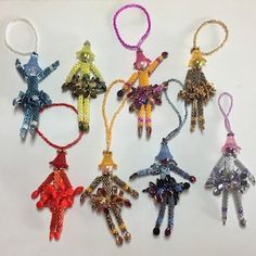 six different colored beaded keychains hanging from strings on a white table top