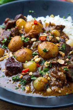 a close up of a plate of food with meat and potatoes on rice, garnished with parsley