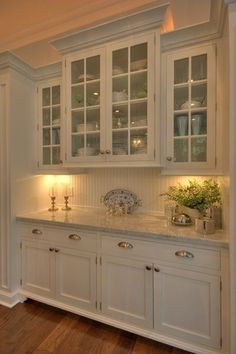 a kitchen with white cabinets and marble counter tops