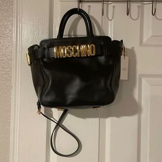 Black Leather Moschino Bag. Logo Plaque Bag. Office Bag With Logo Hardware And Double Handle, Classic Tote Satchel With Logo Hardware, Classic Tote Satchel, Formal Tote Shoulder Bag With Logo Hardware, Black Double Handle Bag With Logo Hardware, Luxury Tote Satchel With Logo Hardware, Chic Double Handle Satchel With Logo Hardware, Black Satchel With Logo Hardware And Double Handle, Black Double Handle Satchel With Logo Hardware