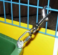 a close up of a green and yellow bird cage with a metal chain attached to it