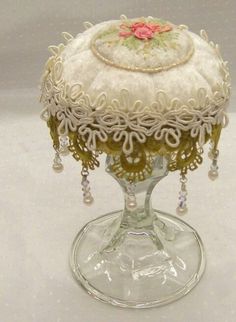 a glass vase with a decorative lid and bead trimmings on the base