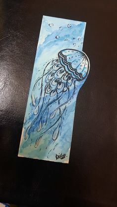 a watercolor drawing of a jellyfish on a piece of paper that is sitting on a table