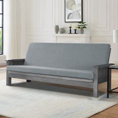 a living room with a gray couch and white rug in front of a fire place