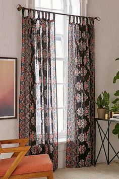 the curtains in this room are black and white with red flowers on them, while the window