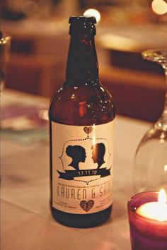 a bottle of beer sitting on top of a table next to a candle