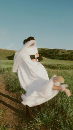 a woman in a white dress and veil is running through the grass with her legs spread out