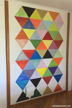 a colorful quilt hanging on the wall next to a wooden frame with an arrow in it