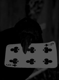 a man holding up a playing card in front of his face with an evil look on his face