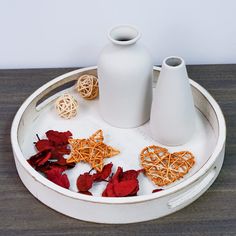 two white vases sitting on top of a wooden table next to dried flowers and other items