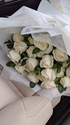 a bouquet of white roses sitting in the back seat of a car