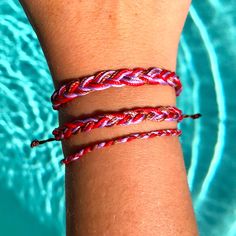 a close up of a person's arm wearing three different colored rope bracelets