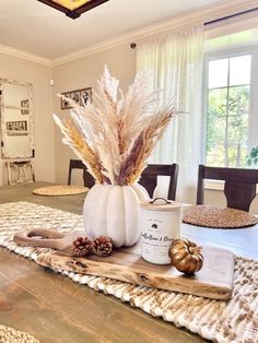 a dining room table is decorated with white pumpkins and dried grasses